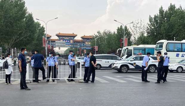 Police officers wearing face masks are seen outside an entrance of the Xinfadi wholesale market, which has been closed for business after new coronavirus infections were detected, in Beijing yesterday.