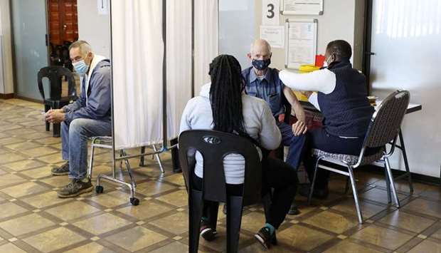 A man is vaccinated as another looks on while waiting to receive a dose of a coronavirus disease (Covid-19) vaccine in Meyerton, south of Johannesburg, South Africa
