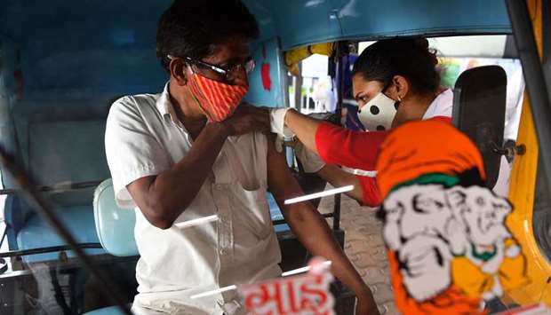 A health worker inoculates a auto-rickshaw driver with a dose of a vaccine against the Covid-19 coronavirus, at a drive-through vaccination centre inside a shopping mall in Mumbai 