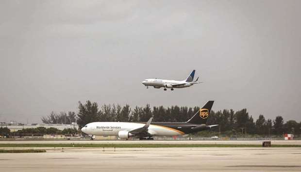 A cargo aircraft operated by United Parcel Service (UPS) taxis as a passenger aircraft operated by United Airlines Holdings makes a descent at Miami International Airport. United is expected to take upwards of 150 of Boeing 737 MAX jetliners and more than 50 Airbus A321neos, sources say.