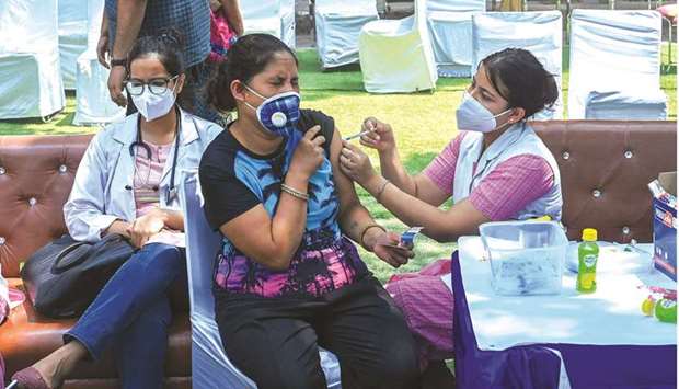 A health worker inoculates a woman with a dose of the Covishield vaccine against Covid-19 at a temporary vaccination centre in New Delhi.