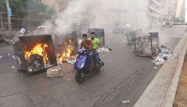 Two men ride past burning garbage bins during a protest at a main road in Lebanonu2019s capital Beirut against dire living conditions amidst the ongoing economical and political crisis, yesterday.