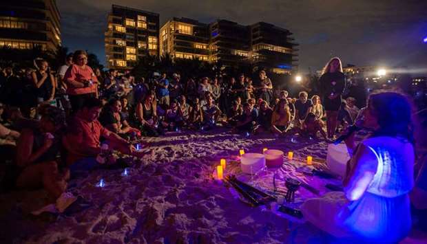 People attend a community vigil on the beach for those missing after the collapse of the Champlain Towers South condominium building in Surfside, Florida