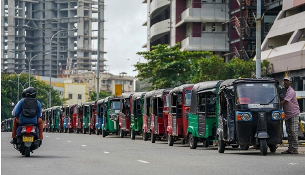 Autorickshaw drivers queue along a street to buy petrol from a Ceylon petroleum corporation fuel station in Colombo. AFP