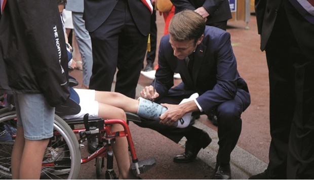 French President Emmanuel Macron signs a boyu2019s leg plaster before voting during the final round of the countryu2019s parliamentary elections, in Le Touquet, France yesterday. (Reuters)