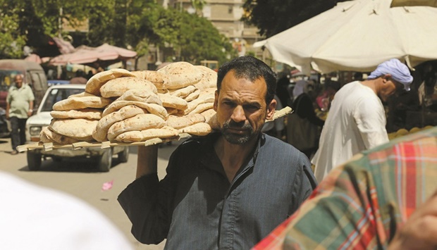 An Egyptian man is holding bread in the vegetables market in Cairo (file). The highest level in three years, inflation was driven by a 24.8% increase in food and beverage prices, the largest single component of the inflation basket.