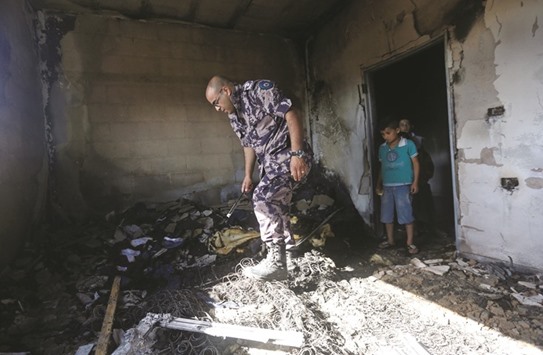 A member of the Palestinian security forces inspects a damaged house following a blaze overnight in the village of Duma in the Israeli-occupied West Bank yesterday.