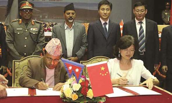 Yu Hong, right, and Lok Darshan Regmi, left, sign documents  during the handover ceremony in Kathmandu.