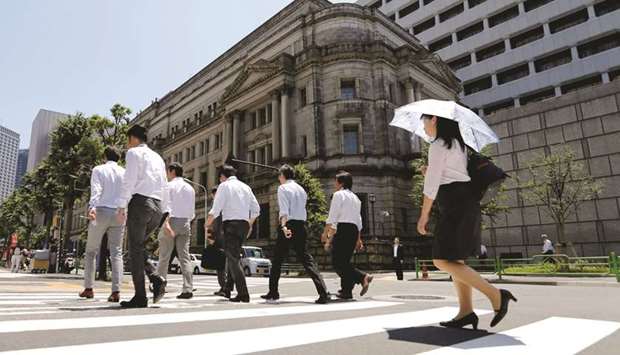 People walk past the Bank of Japan building in Tokyo. The BoJ pledged to maintain its monetary stimulus programme, including keeping the 10-year yield around 0%, as it delayed reaching an inflation goal by a year.