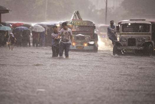 People wade on a flooded street caused by a sudden heavy rain in Manila, yesterday.  Health officials have said that the surge in leptospirosis cases can be attributed to seasonal flooding due to continuous rains in recent weeks.