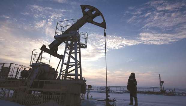 A worker inspects a pumping jack during drilling operations in an oilfield in Russia.