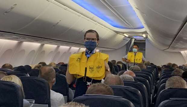 Flight attendants of TUI Fly wear face masks as they give instructions to German tourists on the first flight from Duesseldorf to Mallorca, two weeks before Spain starts reopening borders closed since mid-March to curb the coronavirus disease pandemic, in Duesseldorf, Germany