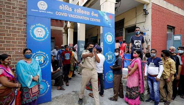 A police officer manages people who came to receive a dose of a coronavirus disease (Covid-19) vaccine outside a vaccination centre in Ahmedabad, India