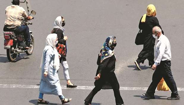 Iranians, mask-clad due to the coronavirus pandemic, cross a street in the capital Tehran, yesterday.