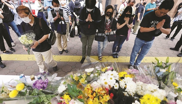 People pray next to flowers laid at the site where late former Japanese Prime Minister Shinzo Abe was shot while campaigning for a parliamentary election, near Yamato-Saidaiji station in Nara, yesterday.