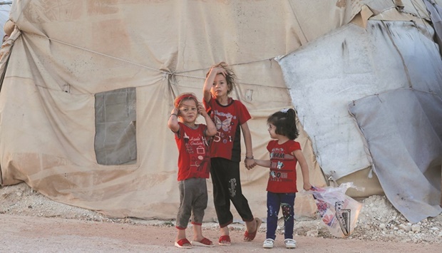 Children stand together outside a tent at the u201cBlue campu201d for Syrians displaced by conflict near the town of Maaret Misrin in the rebel-held northern part of the northwestern Idlib province during the Eid  al-Adha holiday, yesterday.