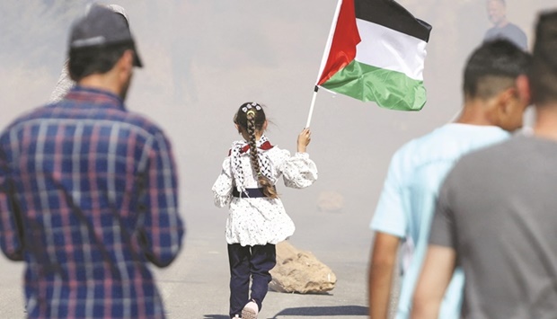 A Palestinian girl carries her countryu2019s national flag during demonstrations against Israeli settler attacks in the occupied West Bank, yesterday.