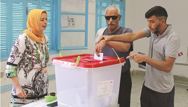 A Tunisian voting official assists an blind man during a referendum on a draft constitution put forward by the countryu2019s President, at a polling station in Kasserine, yesterday.