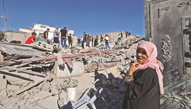 People gather after security forces demolished the home of one of the Palestinian fighters, in the village of Qarawet Bani Hassan in the occupied West Bank, yesterday.