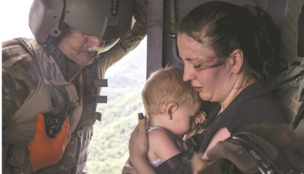 Command Sergeant Major Tim Lewis of the Kentucky National Guard secures Candace Spencer, 24, while she holds her son Wyatt Spencer, 1, after being airlifted yesterday from South Fork, Breathitt County, Kentucky. (AFP)