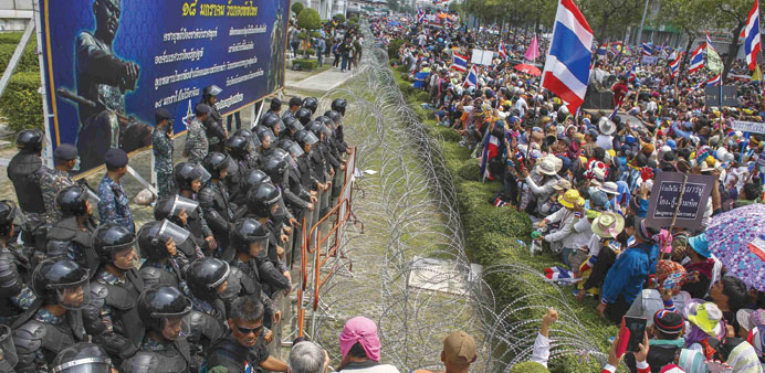 Anti-government protesters gather as Thai soldiers stand guard at a Defence Ministry compound serving as a temporary office for Thai Prime Minister Yi