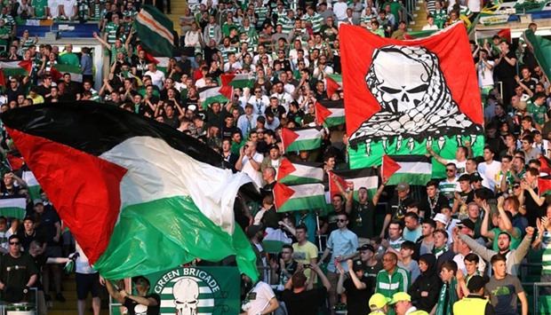 The Celtic fans hold aloft flags emblazoned with the Palestinian colors and skulls wrapped in the traditional Arab keffiyeh head dress during the first leg play-off in Glasgow against Hapoel Beersheba. Reuters