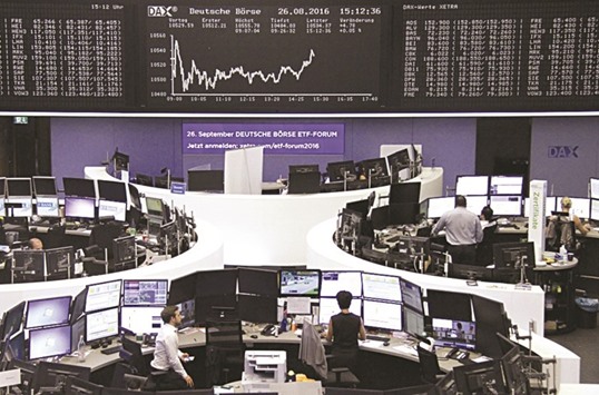 Traders work at their desks in front of the DAX board at the Frankfurt Stock Exchange. The DAX 30 index closed up 0.5% at 10,587.8 points yesterday.