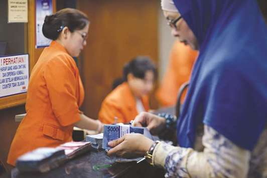 A customer counts Indonesian rupiah banknotes at a currency exchange office in Jakarta. The worldu2019s most populous Muslim nation is moving towards the creation of a supportive framework for Shariah-compliant banking.