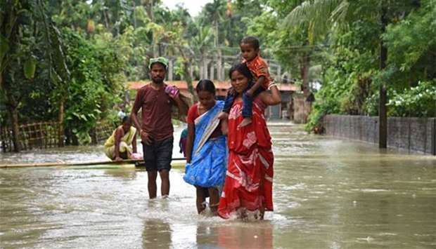 A woman carries her child as she and others wade through a flooded road in Jakhalabandha area in Nagaon district in the northeastern state of Assam, on Monday.