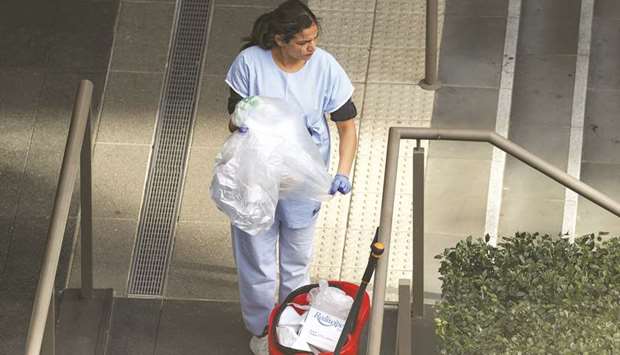 A worker disposes of waste outside a quarantine hotel where returning travellers are kept in isolation for a period to curb the spread of the coronavirus disease in Sydney.