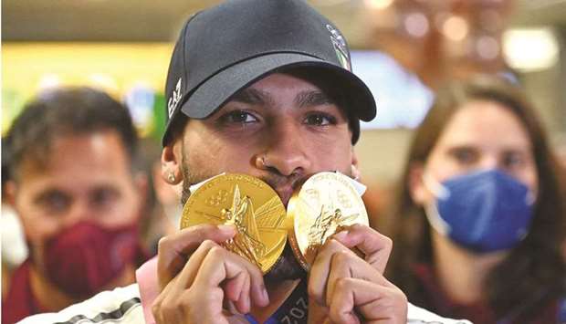 Italyu2019s 100m and 4x100m relay gold medal winner Lamont Marcell Jacobs poses with his medals as he arrives from the 2020 Tokyo Olympics at Romeu2019s Fiumicino Airport. (AFP)