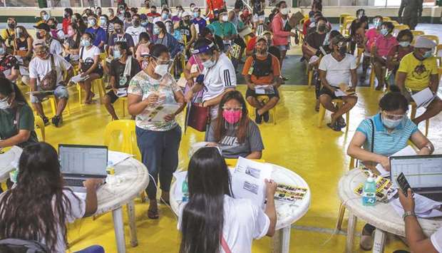 Individuals line up to receive cash aid from the national government during enhanced community quarantine at a basketball court in Manila yesterday.