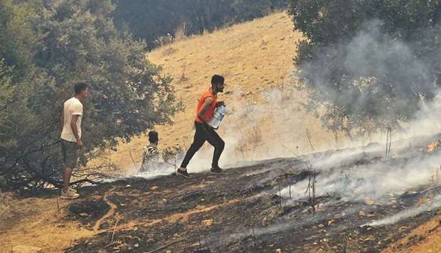 Volunteers attempt to put out a fire in the forested hills of the Kabylie region.