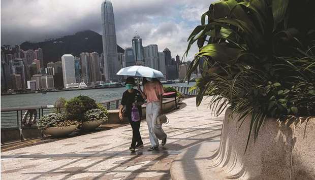 Two women walk along Victoria Harbour in the Kowloon district of Hong Kong yesterday.
