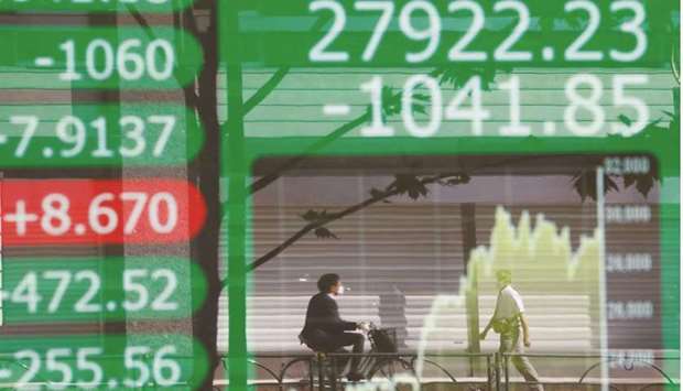 People are reflected on an electronic board showing Nikkei and its graph outside a brokerage in Tokyo. The Nikkei 225 closed down 1.1% to 27,281.17 points yesterday.