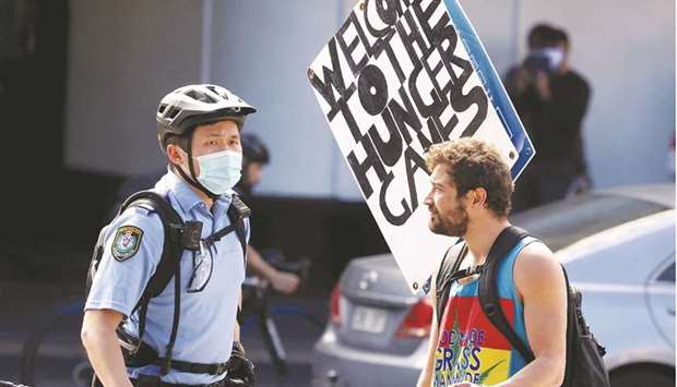 A police officer stops a protester with placards in Sydney following calls for an anti-lockdown protest rally amid a fast-spreading coronavirus outbreak.
