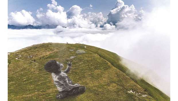 An aerial photograph taken of the top of Moleson mountain, in the Swiss Prealps, shows a giant land art fresco by artist Guillaume Legros, known as Saype, entitled A new breath, representing a boy blowing clouds