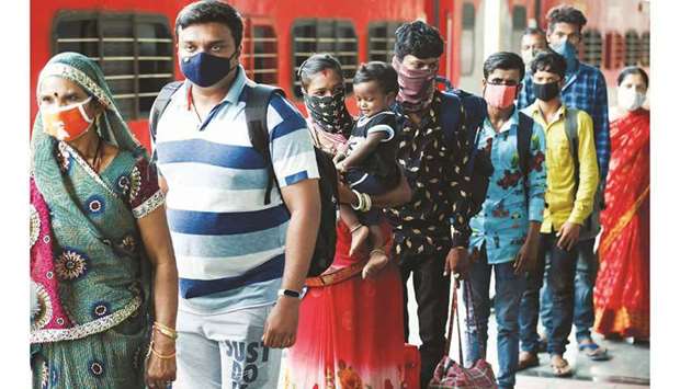 Commuters wait in a queue to have their temperature checked amidst the spread of the coronavirus disease at a railway station in Mumbai, India, yesterday.