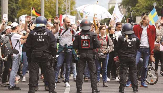 Demonstrators rally against government measures to curb the spread of Covid as security personnel stand guard in Berlin yesterday. (Reuters)