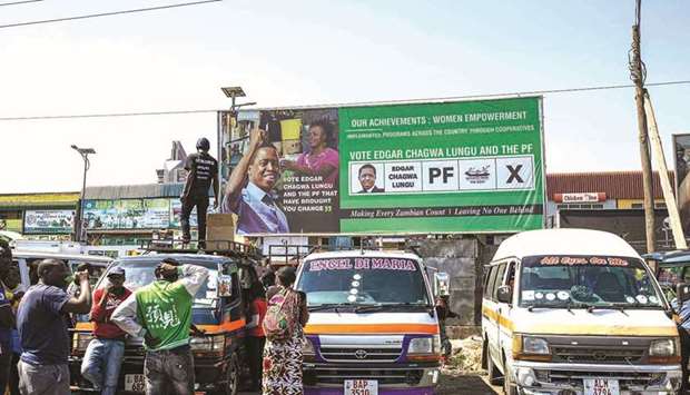People stand by a poster of incumbent Zambian president Edgard Lungu at City Market in Lusaka.