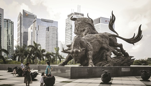 People stand in front of a sculpture of bulls at the entrance to the Shenzhen Stock Exchange building in China. The Composite closed up 0.2% to 3,259.96 points yesterday.