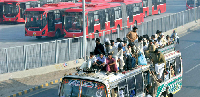    Pakistani commuters travel on a overloaded private bus beside the metro bus terminal in Lahore.