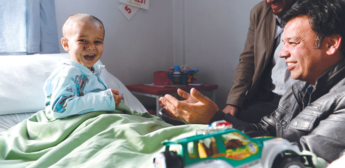 Abuzar Ahmad, the youngest son of slain Afghan AFP reporter Sardar Ahmad, plays during a visit by his uncle Bashir Mirzad (right) and AFP Bureau Chief