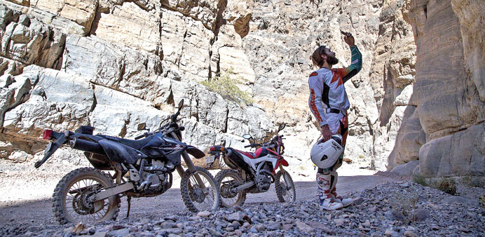 TAKING A PICTURE: On a break from desert riding, Mark Buche, uses his phone to photograph the beauty of Titus Canyon Narrows.