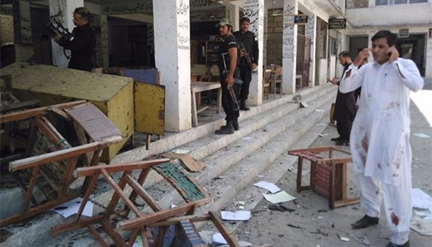 Pakistani police inspect the site of a suicide bomb attack at a district court in Mardan on Friday.