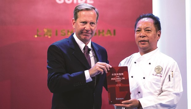 Master chef of Canton 8, Jie Ming Jian (right) is awarded at a ceremony by international director of the Michelin Guides Michael Ellis with two stars in Shanghai yesterday.