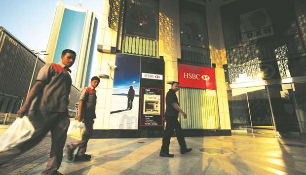 Workers pass by an HSBC Bank branch in downtown Manama. Bahrain is the only one of six oil-exporting states in the GCC that is rated junk by all three major credit rating agencies.