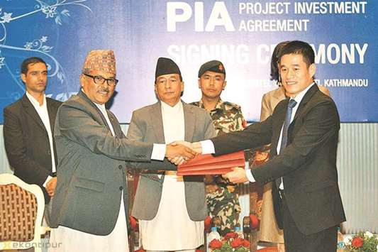 Maha Prasad Adhikari and Lai Weipeng exchange documents after signing a deal.