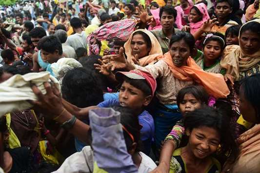 Newly arrived Rohingya refugees receive relief supplies at Kutupalong refugee camp in the Bangladeshi locality of Ukhia yesterday.