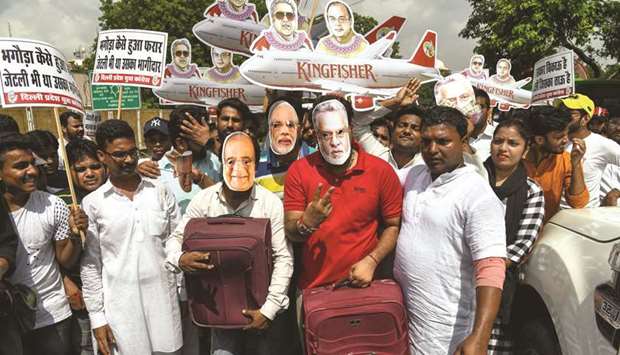 Activists and supporters of the Congress party wear masks bearing images of Finance Minister Arun Jaitley, businessman Vijay Mallya and Prime Minister Narendra Modi as they protest in New Delhi yesterday against the BJP for allegedly allowing Mallya to leave the country.